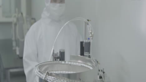 scientist operate vaccine capping process in automated pharmaceutical production line manufacturing, cap placing on vials of vaccine injections drugs in a sterile factory environment setting.