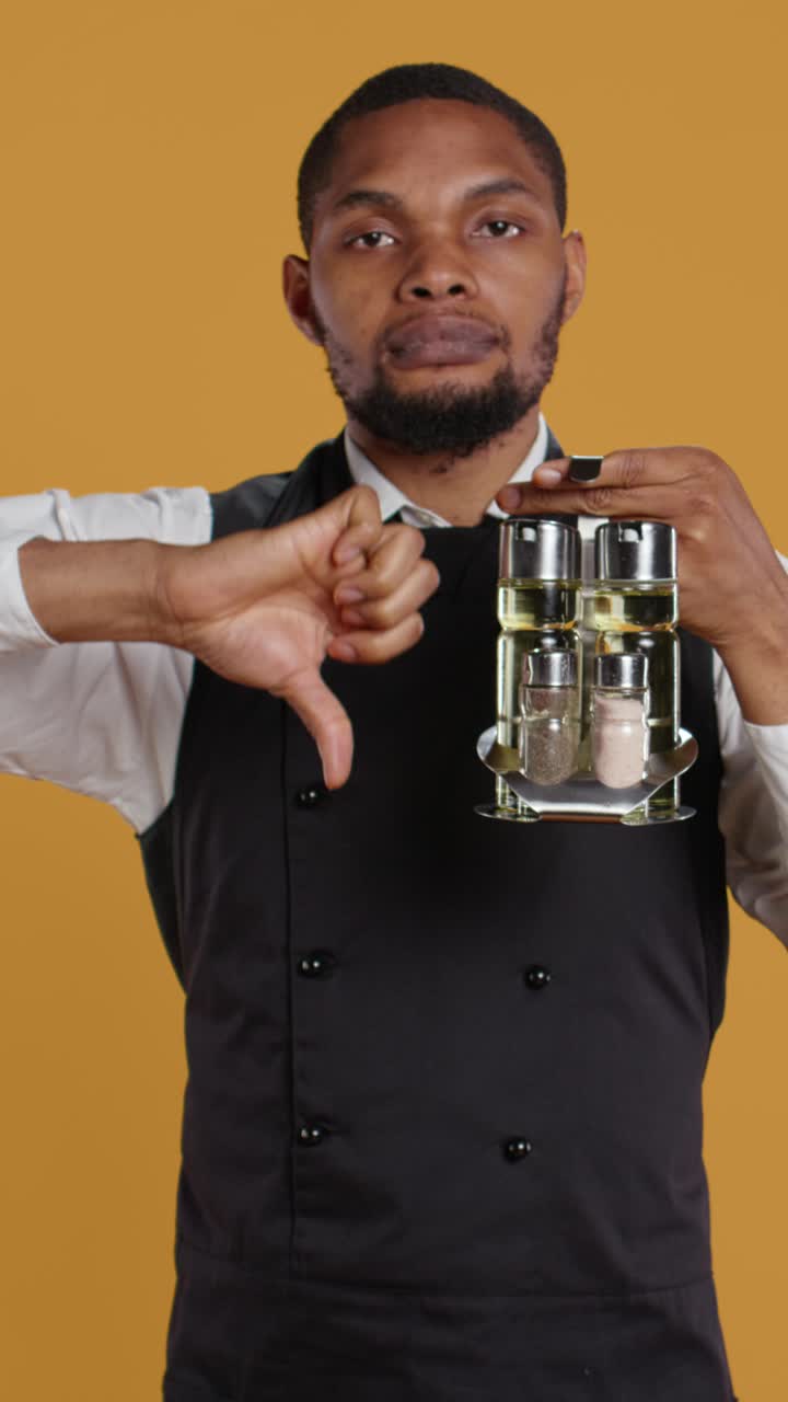 Chef afroamericano che tiene un porta spezie e mostra il pollice verso