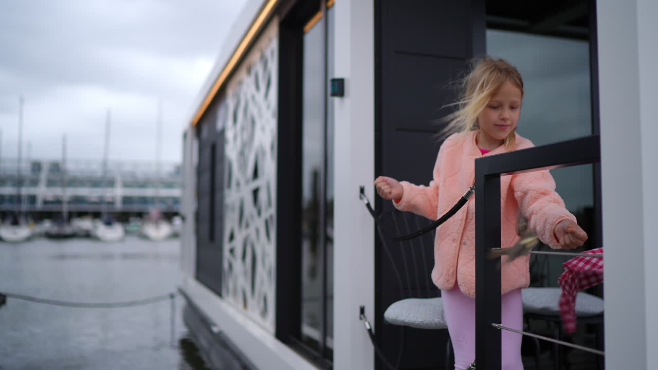 Young girl feeding sparrow near boat railing