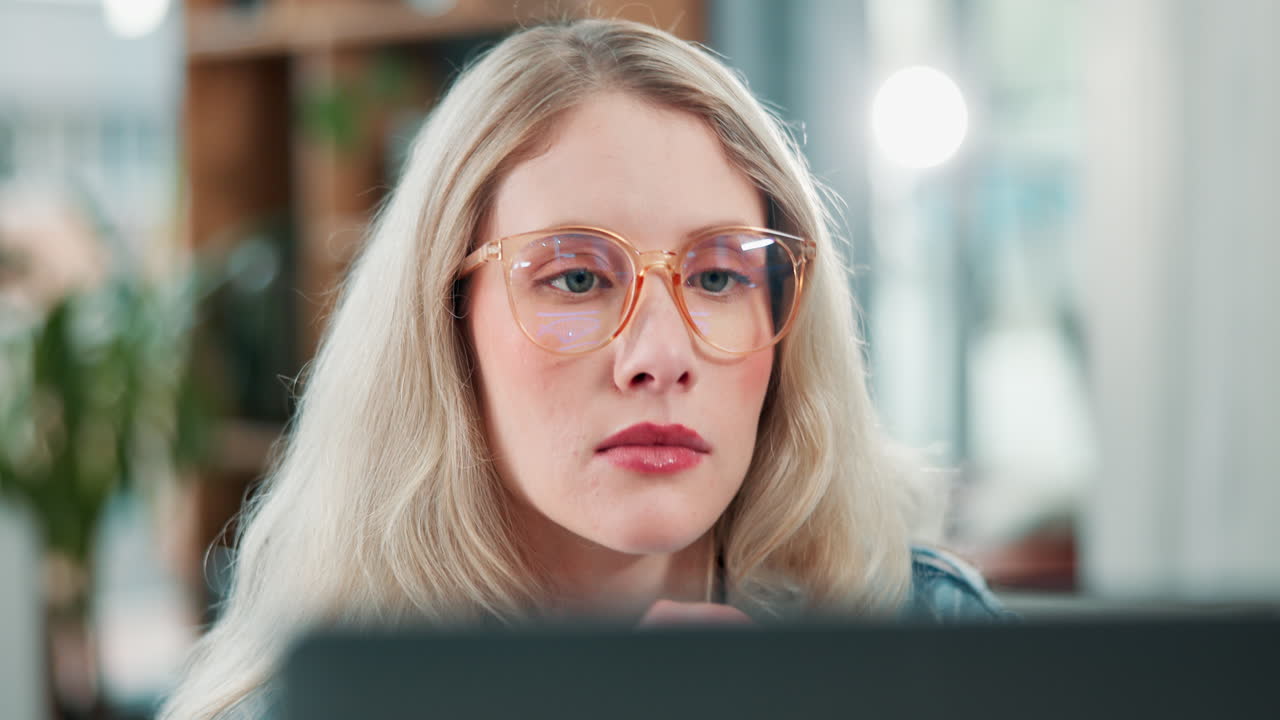 Woman with blonde hair and glasses looking at a computer screen