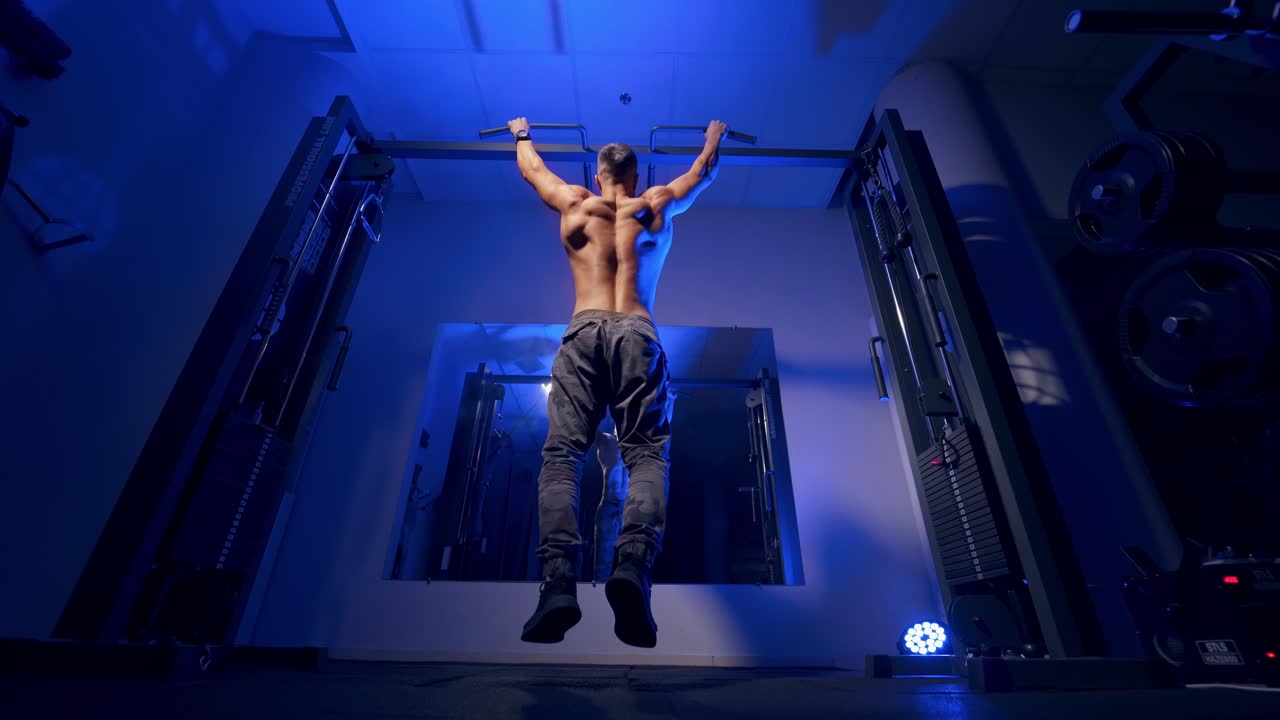 Bodybuilder pulling up on horizontal bar. Athlete muscular fitness male pulling up on horizontal bar in gym