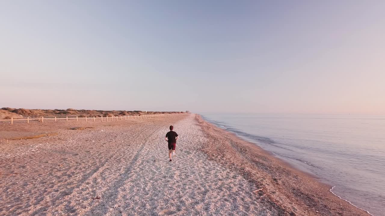 Young athlete runner man with fit strong body training on beautiful sunset at beach