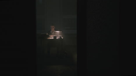 Pale bald accountant looks through the tax papers in the weird room at night