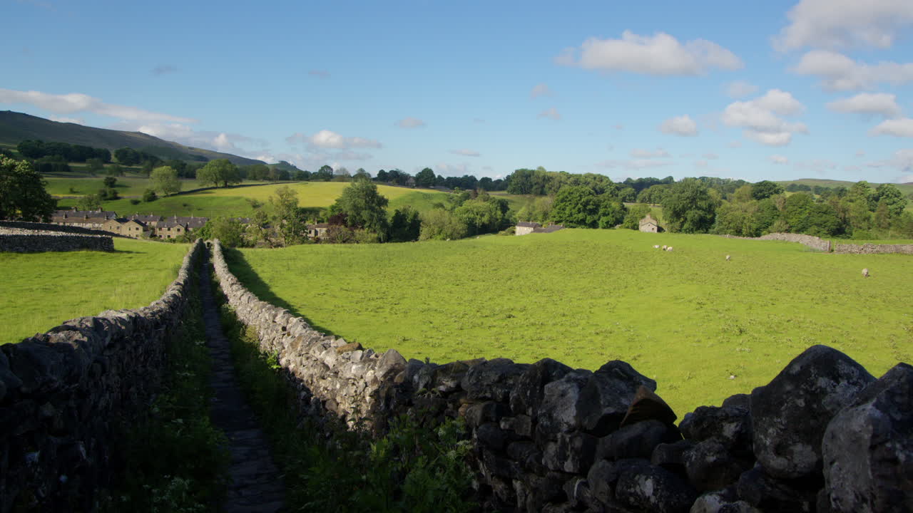 izquierda del marco extra amplia toma de un sendero de piedra seca amurallada con linton en el fondo con una nube ligera