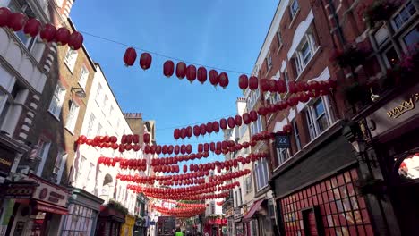 pov walking and looking up at hanging red lanterns in chinatown, london, looking up at a clear blue sky on a sunny morning