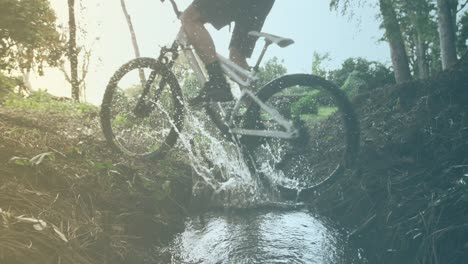 spots of light against mid section of a man riding a bicycle through the puddle