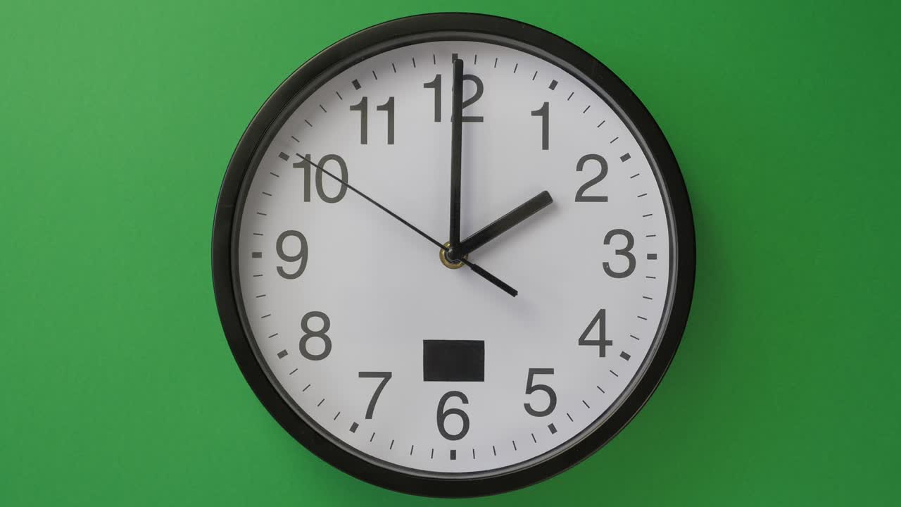 único reloj de oficina blanco colgado sobre un fondo verde