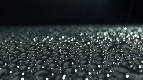 light reflection in the drops on black background. faling drops on glossy surface. abstract law surface.