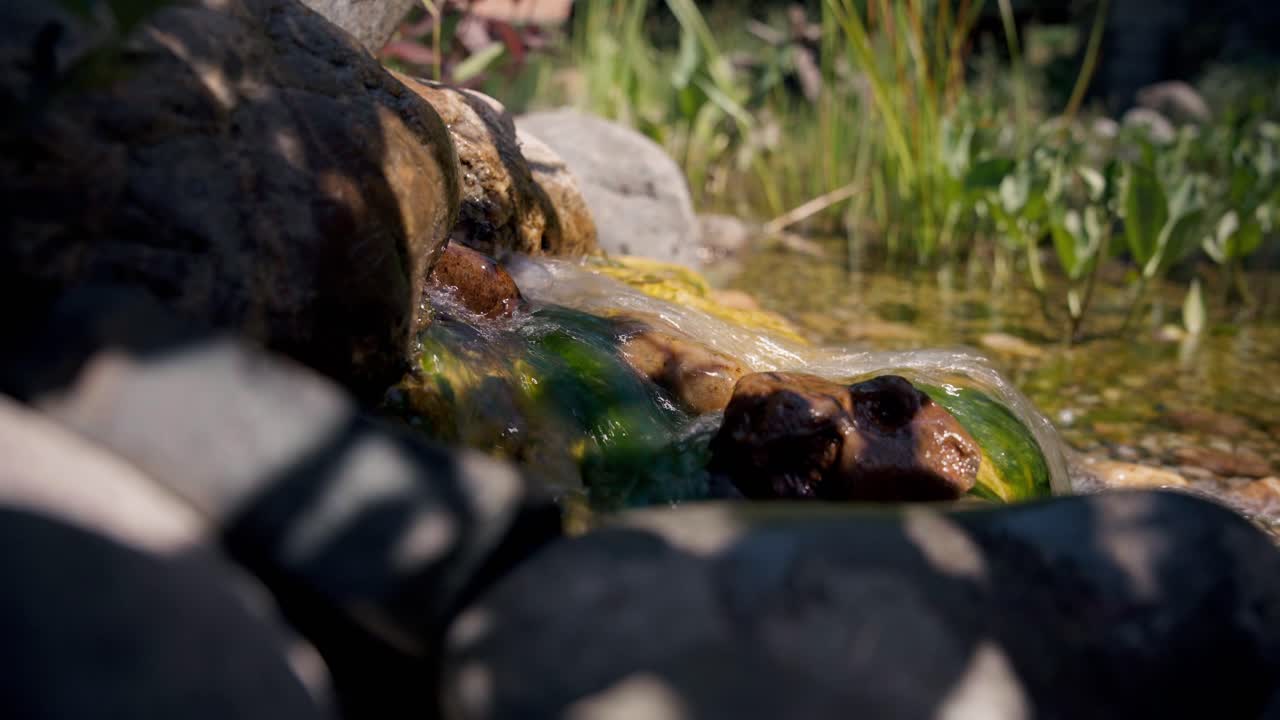 Calm stream flows through decorative rocks in a peaceful garden.