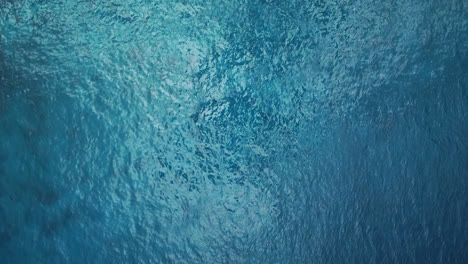 aerial: top down view of blue ocean surface, turquoise sea water background