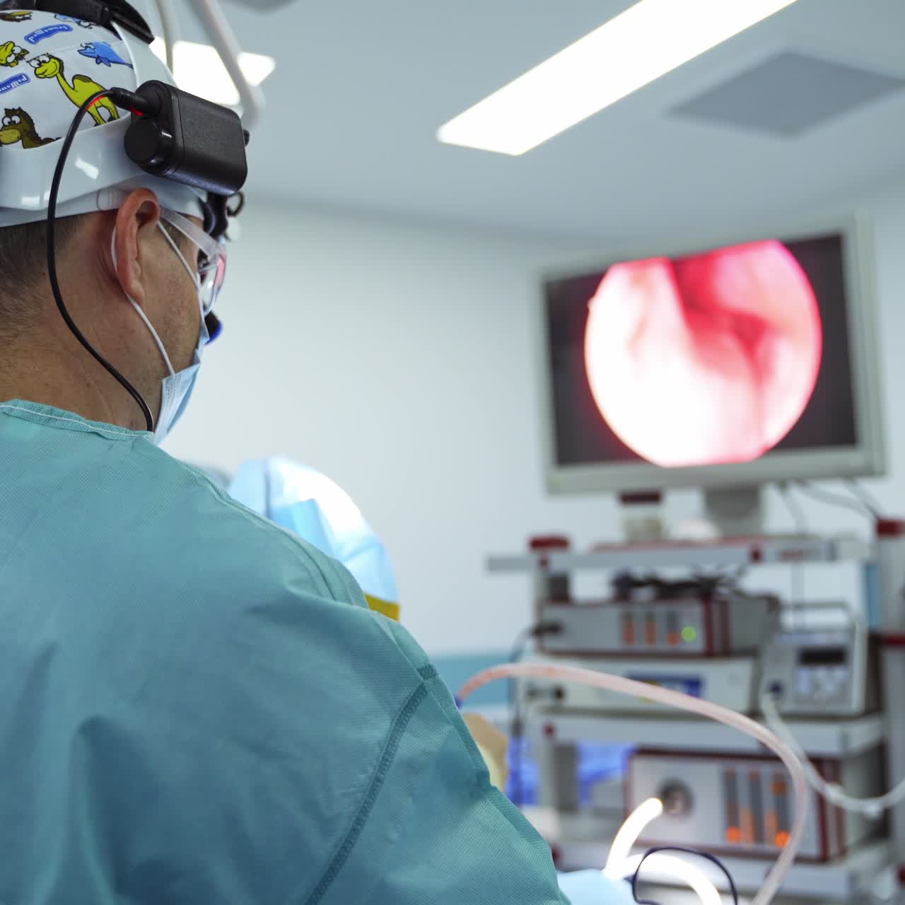 Doctor otolaryngologist stands his back to the camera. Surgeon looks at the screen in front of him. Blurred backdrop