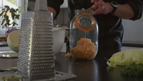 closeup of male adult fermenting food into a glass jar at home kitchen