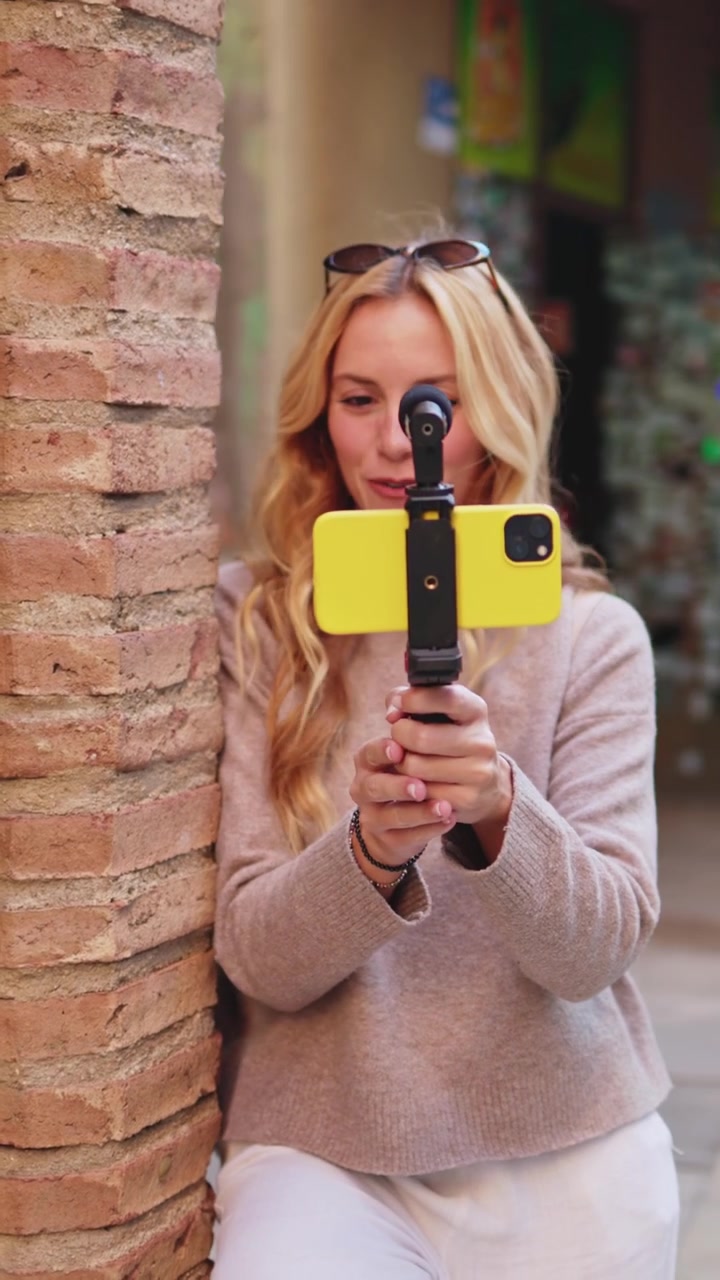 Donna sorridente che fa vlogging con smartphone e microfono all'aperto