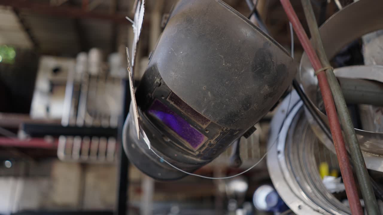 Close-up of a dirty welding helmet hanging in a workshop