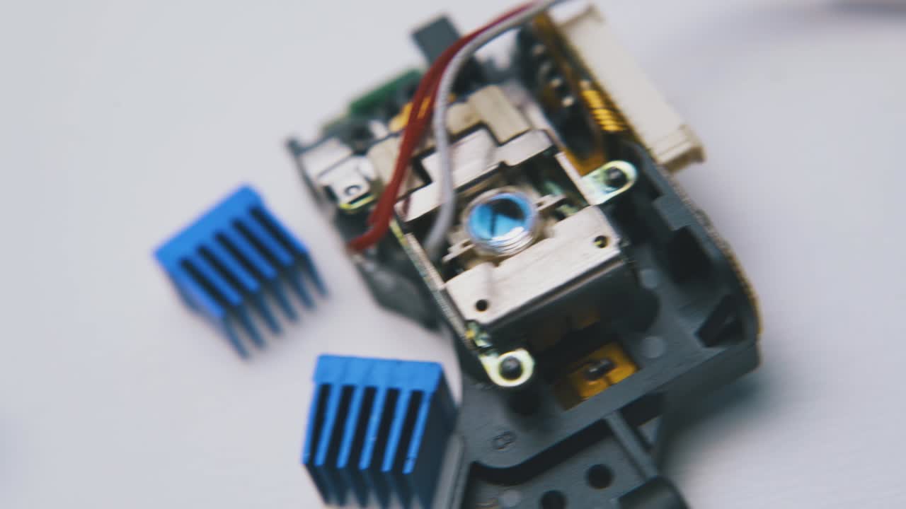 лазерная голова и маленькие зажимы лежат на белой поверхности макро