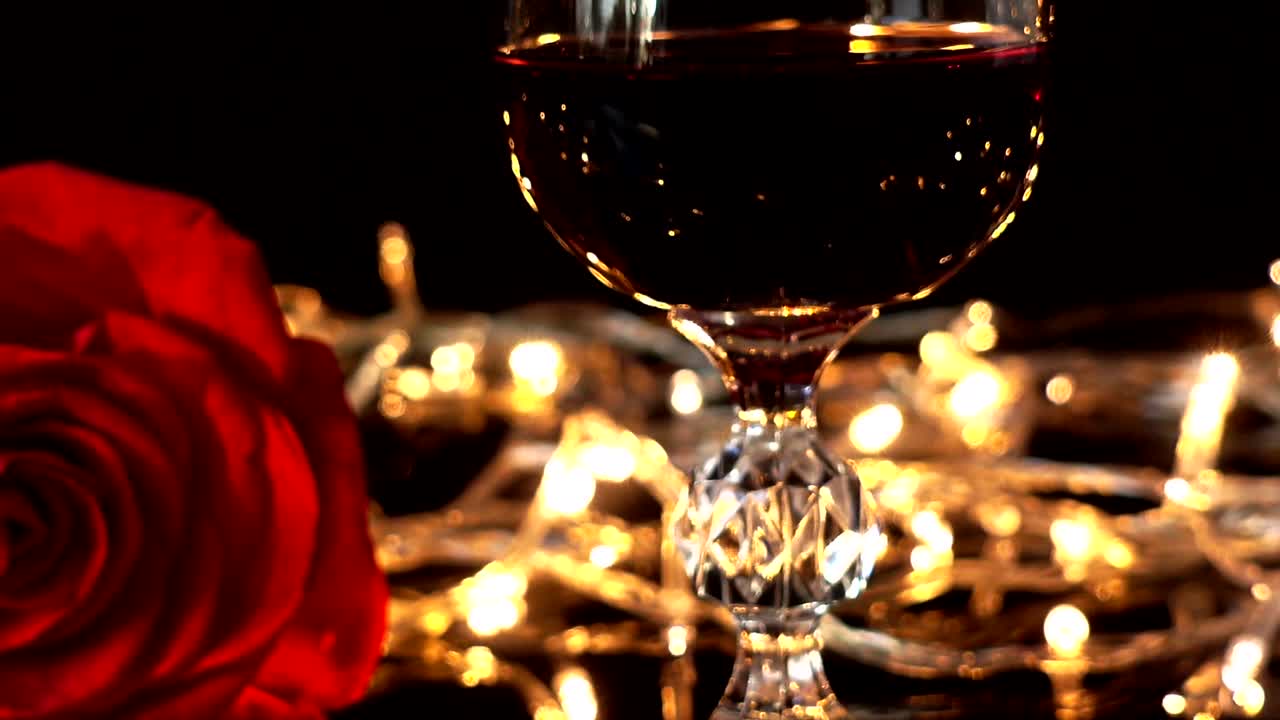 Copas de vino y rosa sobre el fondo de guirnaldas brillantes
