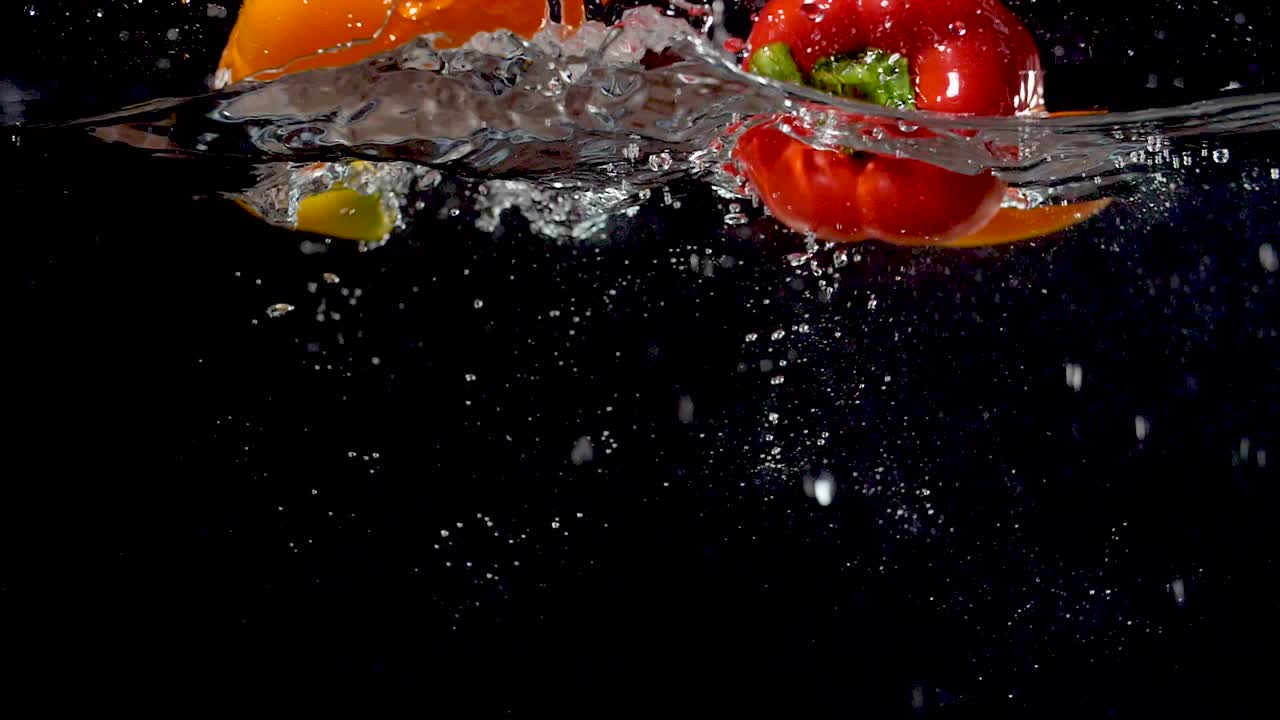 hermosos pimientos que caen al agua en cámara lenta