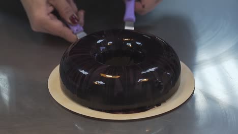 woman slowly puts delicious glazed doughnut on flat plate