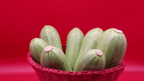 rotating fresh zucchini isolated on red background. close-up