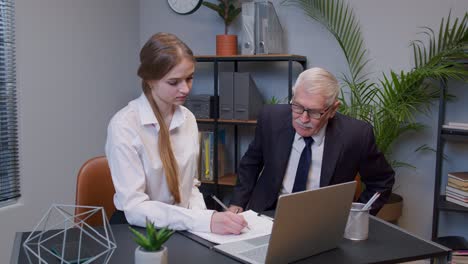 empresario ejecutivo de una empresa examinando datos financieros con una joven secretaria