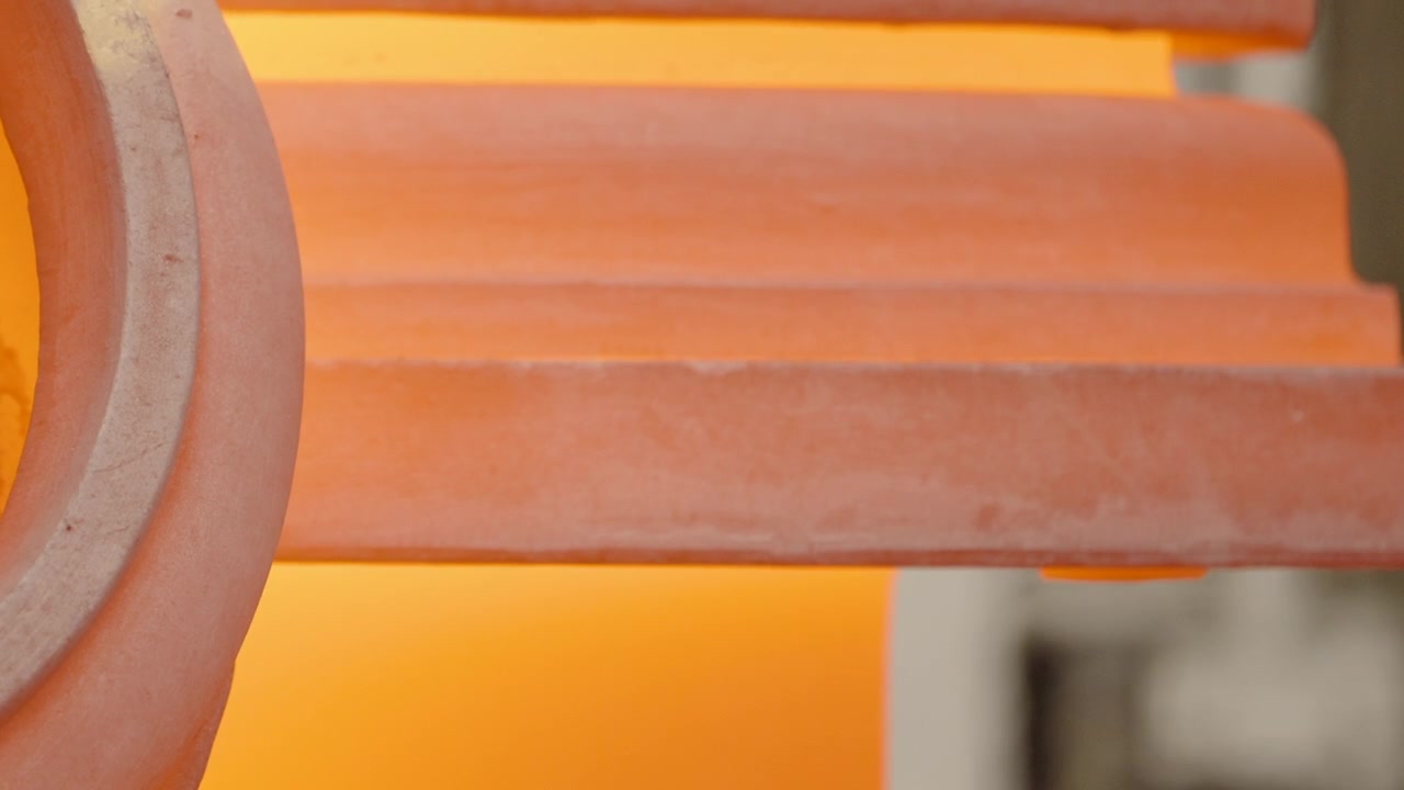 L'acciaio refrattario curvo brilla di arancione contro l'interno luminoso della fornace in un primo piano ravvicinato di una fonderia