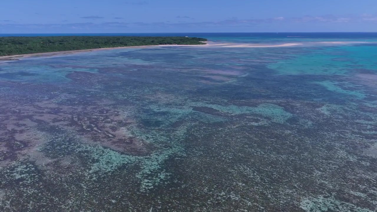 Inquadratura orizzontale con carrellata in avanti, rivolta a destra, sopra le acque basse della barriera corallina e il paesaggio costiero vicino alle spiagge di Kondoi e Kaiji, Isola di Taketomi, Okinawa, Giappone