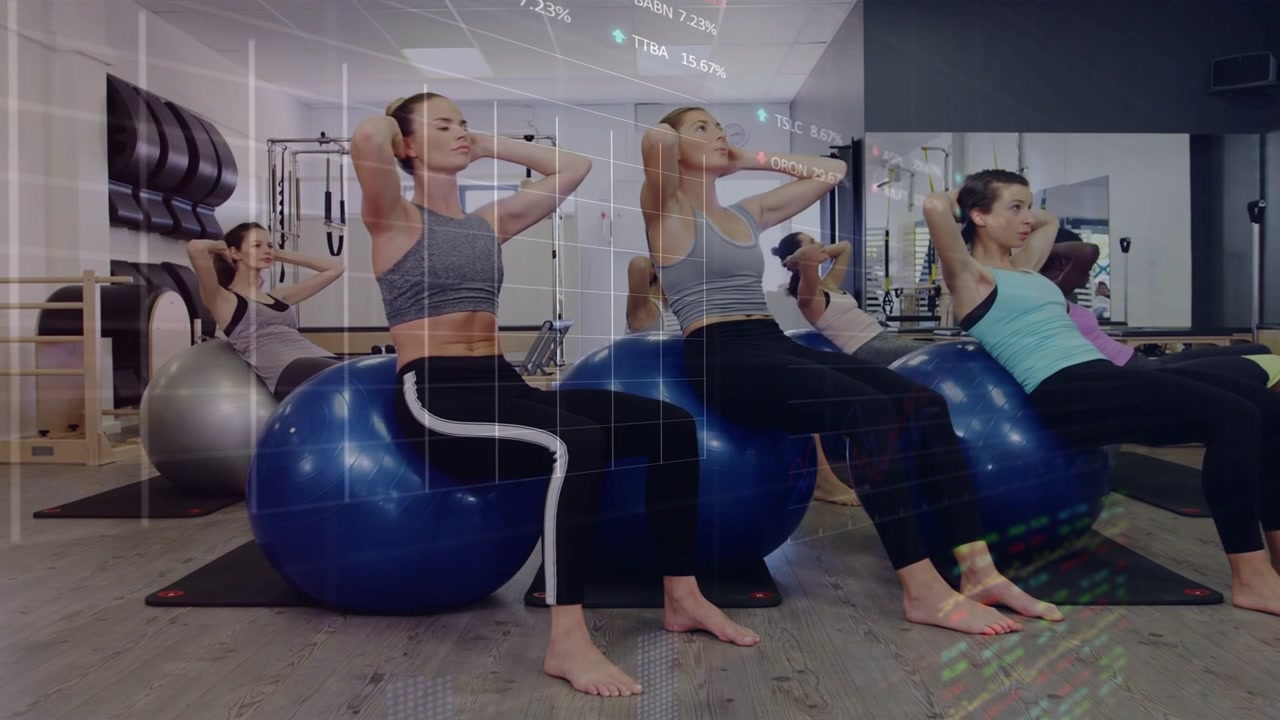 On cue four women performing core curls on balls in fitness studio, mid routine charts overlaying
