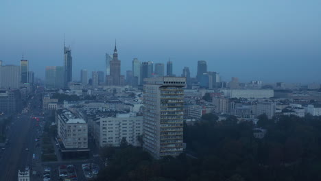 Slide-and-pan-footage-of-tall-old-apartment-building-in-urban-neighbourhood.-Skyscrapers-in-city-centre-in-background.-Warsaw,-Poland