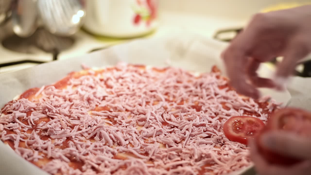 Female hands adding tomatoes into a raw pizza. Slow motion