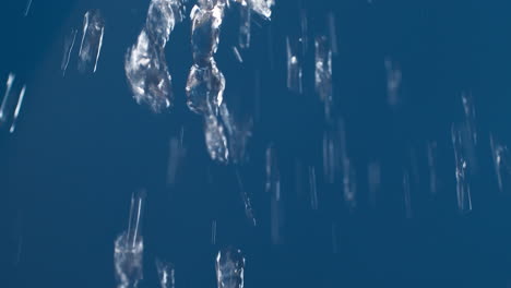 agua pura real que fluye hacia abajo con salpicaduras sobre fondo azul disparando en cámara lenta