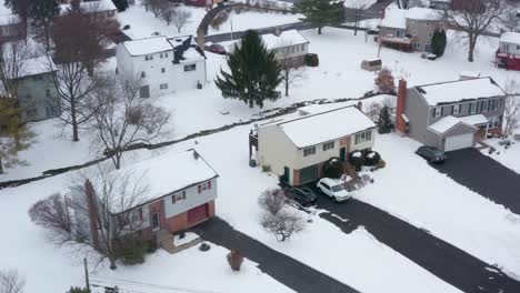 aerial establishing shot of modest split level homes covered in fresh winter snow