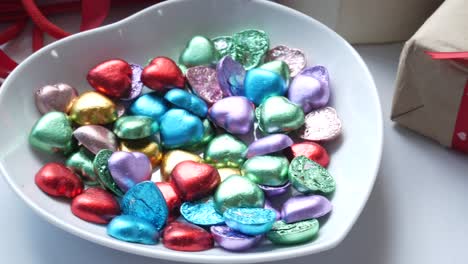 colorful heart-shaped chocolates in a bowl with gifts