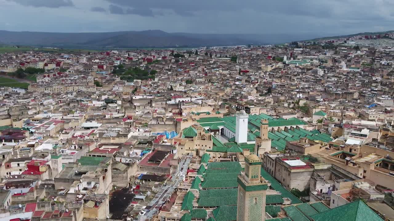 Fes El Bali'nin kalbi üzerinde çarpıcı dron çekimi. Camilerin ve sarayların ikonik yeşil kiremitli çatılarını, antik minareleri ve eski medinanın yoğun geleneksel mimarisini yakalıyor
