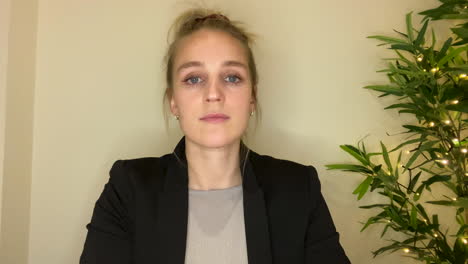 mujer joven en una videollamada de negocios escuchando atentamente mientras mira directamente a la cámara