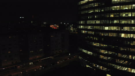 workers doing overtime in a big office building, evening shot with light traffic and a skyscraper in the downtown