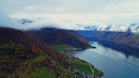 waterfront village on norwegian green fjord on norway with mountains shrouded in clouds