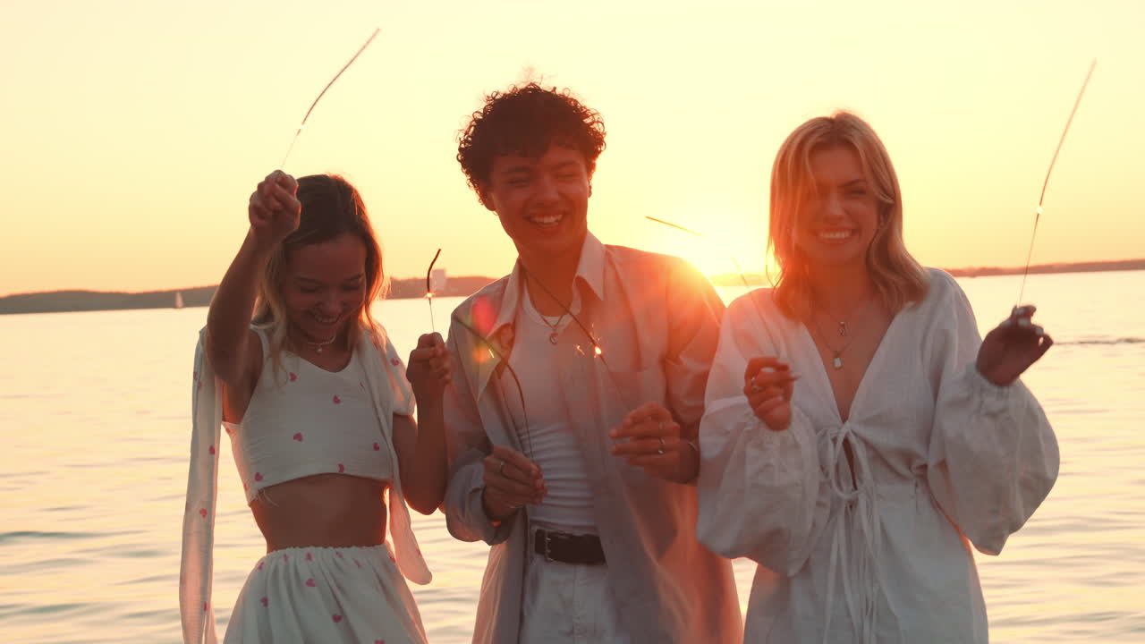 친구 들 이 호수 연안 에서 불 을 들고 해 가 지는 것 을 축하 하고 있다