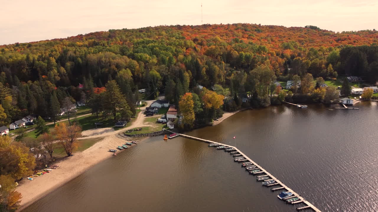 barcos atracados en el complejo cerca de las montañas del bosque con follaje otoñal en el parque provincial de algonquin, ontario, canadá