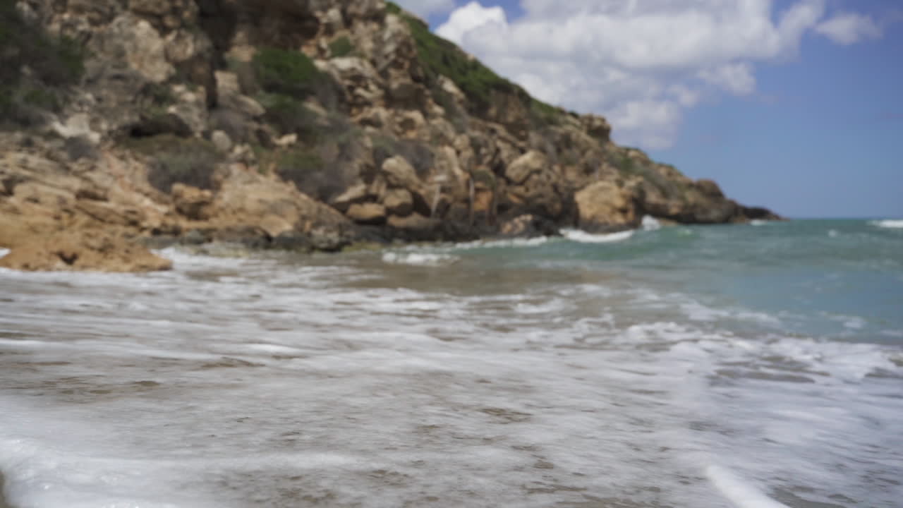 Onde che si infrangono sulla battigia vicino a una roccia al rallentatore