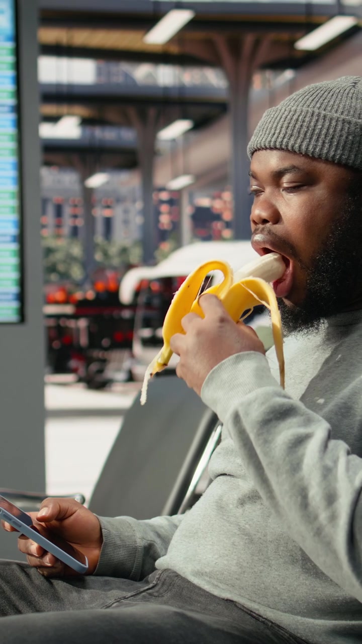 Young Man Eating a Banana While Waiting at the Airport