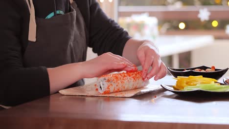 fare il sushi in cucina. mani di donna che arrotolano il sushi fatto in casa.