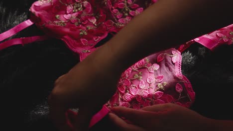 a woman's hand caresses the pink lingerie before dressing it