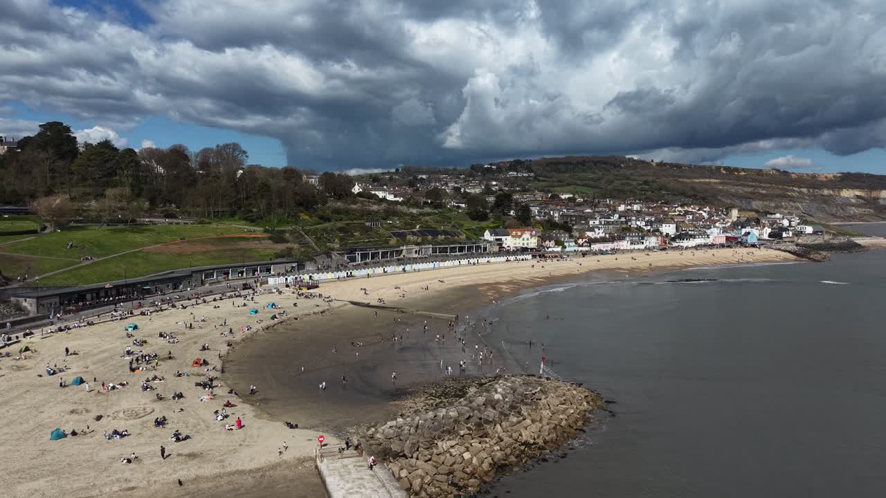 Ripresa aerea panoramica con drone della spiaggia di Lyme Regis, Devon, Regno Unito, con uno sfondo di cielo drammatico