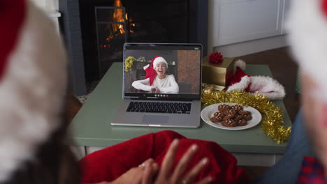 Caucasian-couple-on-video-call-on-laptop-with-female-friend-at-christmas-time