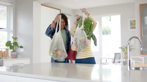 happy diverse couple carrying and unpacking grocery shopping bags in kitchen, slow motion