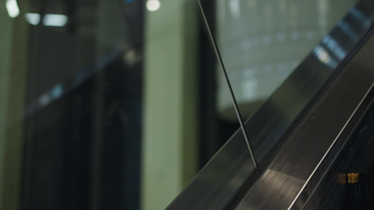 Close up upward movement of escalator in modern shopping mall interior with blurred background lights creating contemporary urban atmosphere highlighting transportation and technology
