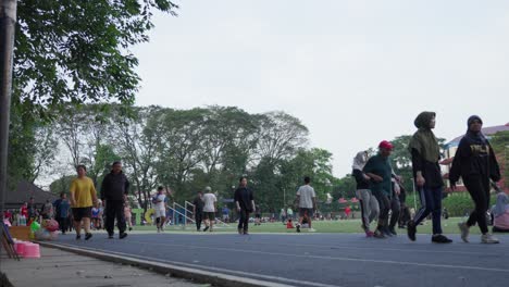 people exercising and walking on a running track in a park