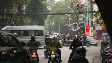 transport vehicles traveling on the street around busy intersection in old town hanoi, vietnam - wide shot