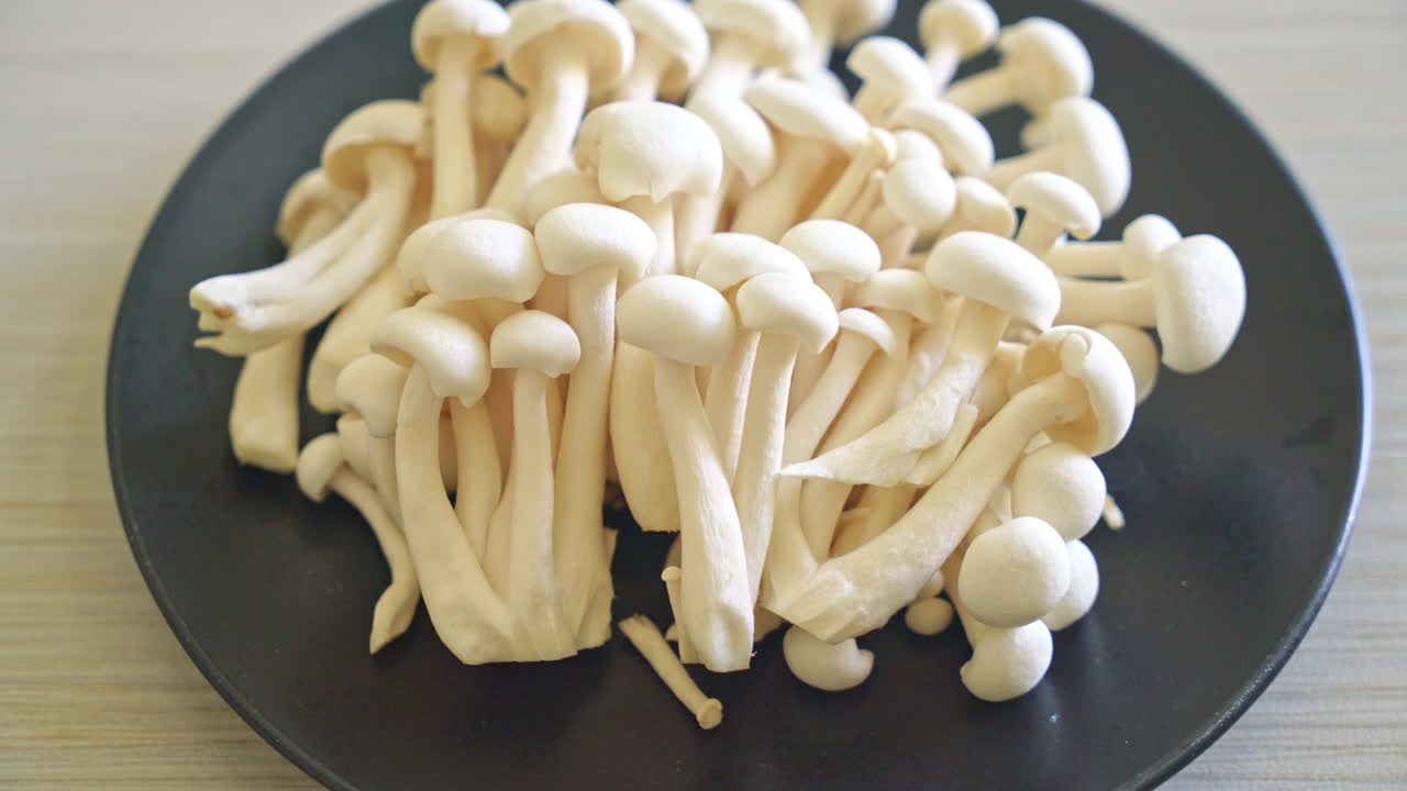 Jamur beech putih segar atau jamur reishi putih di atas piring