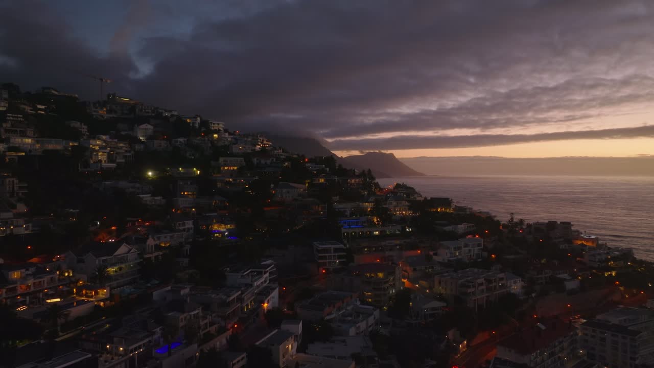 포워드 는 마을 의 주거 건물 위 를 날아간다. 해 가 지는 해변 의 공중 사진. 케이프 타운, 남아프리카 공화국